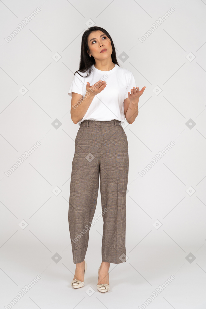Front view of a wondering young lady in breeches and t-shirt raising her hands