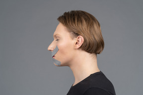 Side view of person with duct tape on mouth and eyes closed