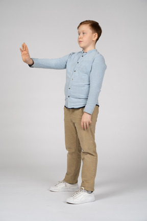 Vista lateral de um menino de um menino de pé com o braço estendido