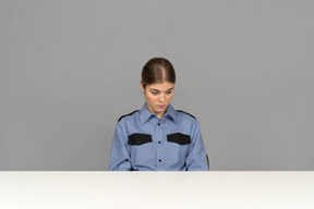 A sad female security guard sitting still