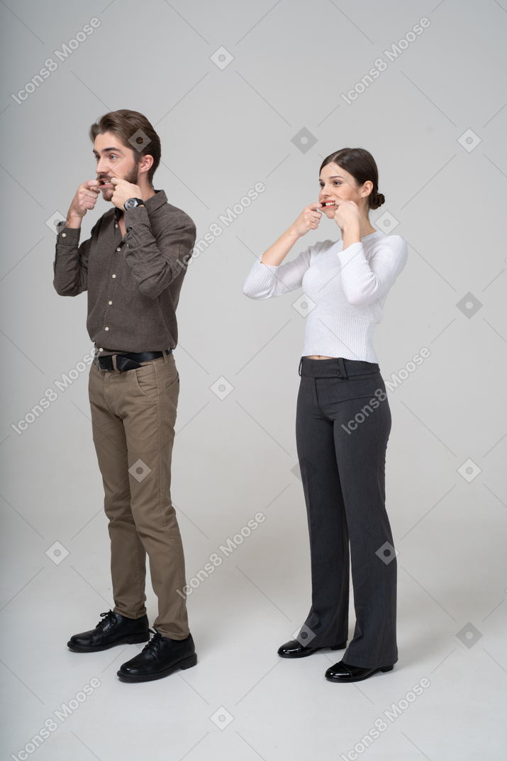 Three-quarter view of a young couple in office clothing stretching mouth