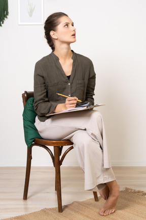 Vue de face d'une jeune femme réfléchie assise sur une chaise tout en passant un test papier