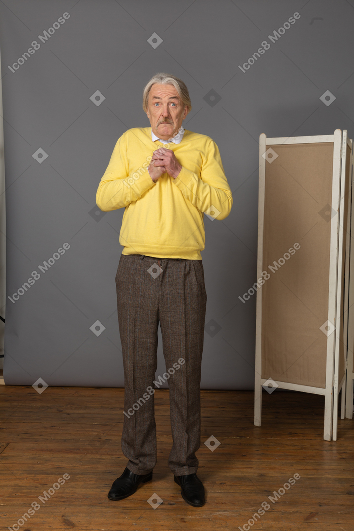 Front view of a surprised old man holding hands together