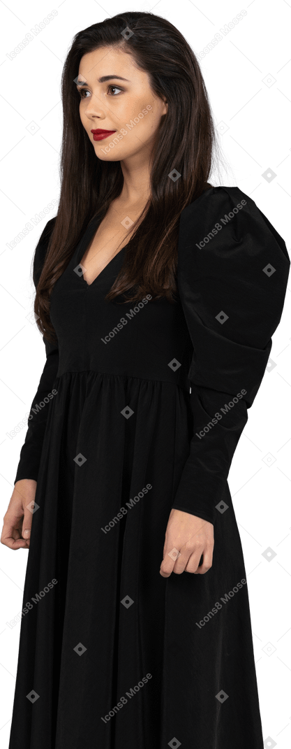 Three-quarter view of a smiling young lady in a black dress standing still
