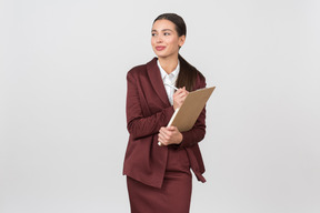 Attractive formally dressed woman taking notes on a clipboard