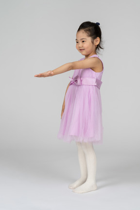 Retrato de una niña con un vestido de tutú extendiendo su brazo izquierdo