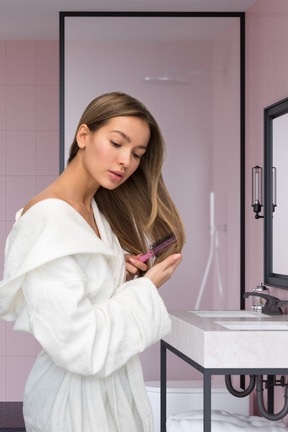 A woman brushing her hair in a bathroom
