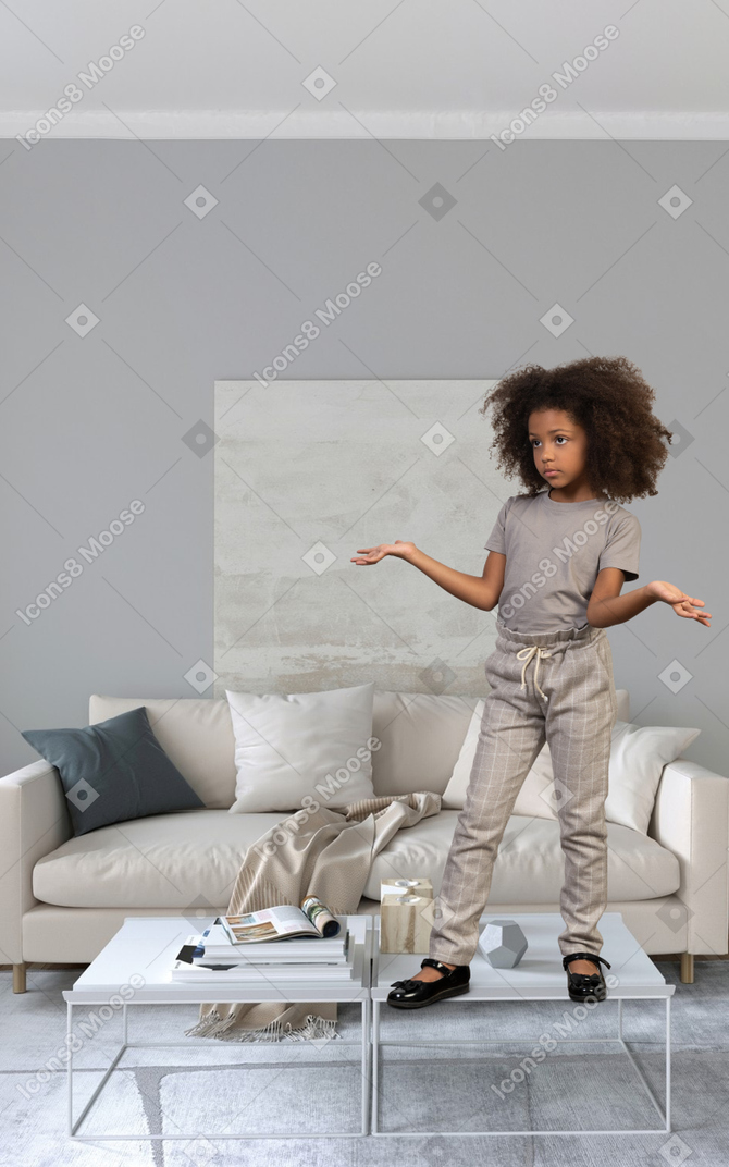 Bored little girl standing on a coffee table
