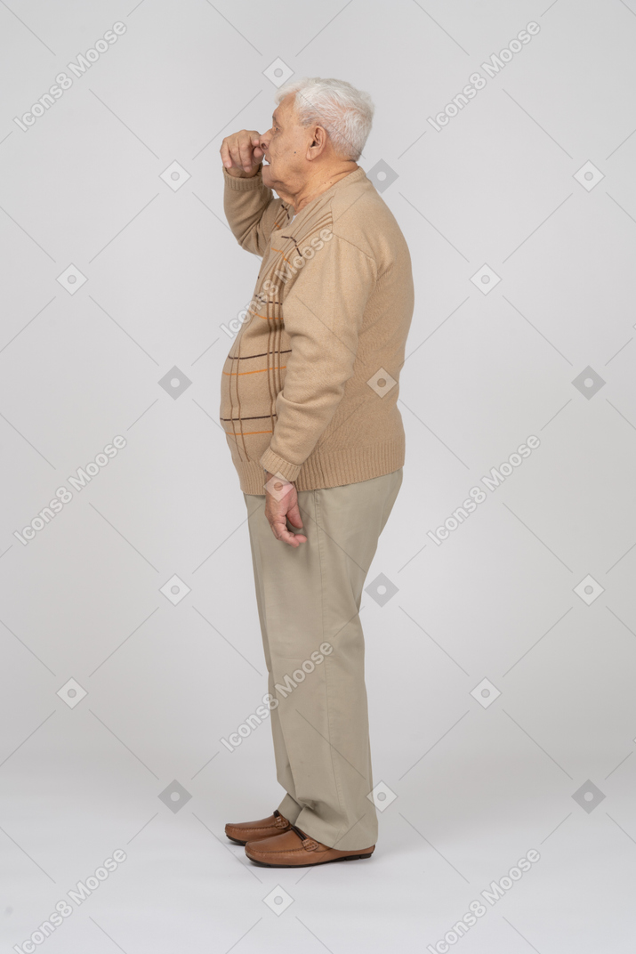 Seitenansicht eines alten mannes in freizeitkleidung, der die nase berührt