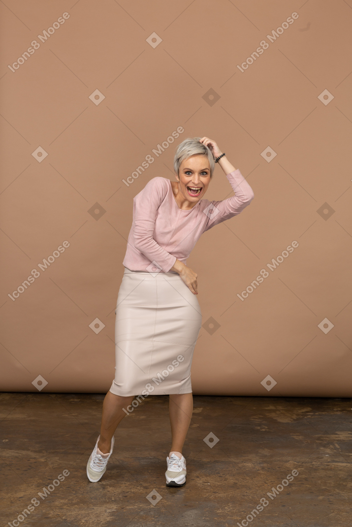 Vue de face d'une femme heureuse dans des vêtements décontractés posant et regardant la caméra