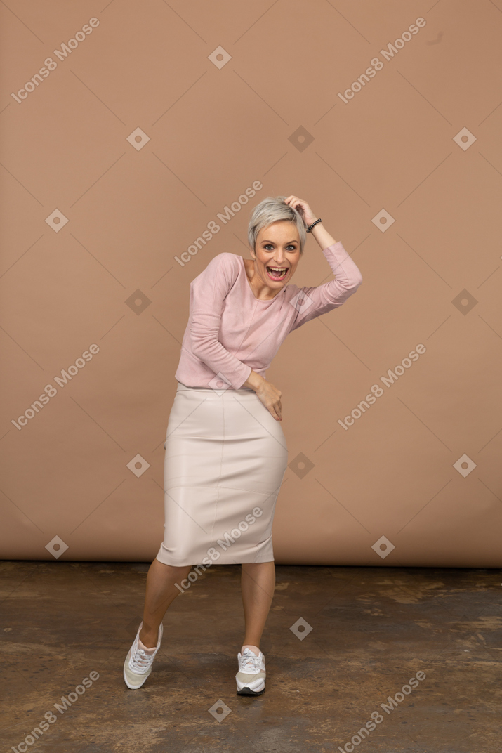 Vista frontal de una mujer feliz en ropa casual posando y mirando a la cámara