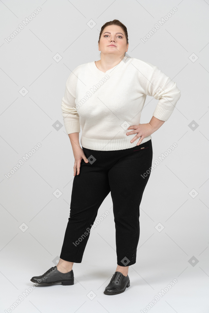 Mujer regordeta en suéter blanco de pie con las manos en las caderas