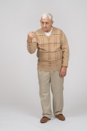 Vista frontal de um velho zangado em roupas casuais, mostrando o punho