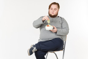 Big bearded guy picking up salad leaf from the plate