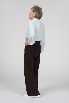 Vista posteriore di tre quarti di una donna anziana con una mano sull'anca