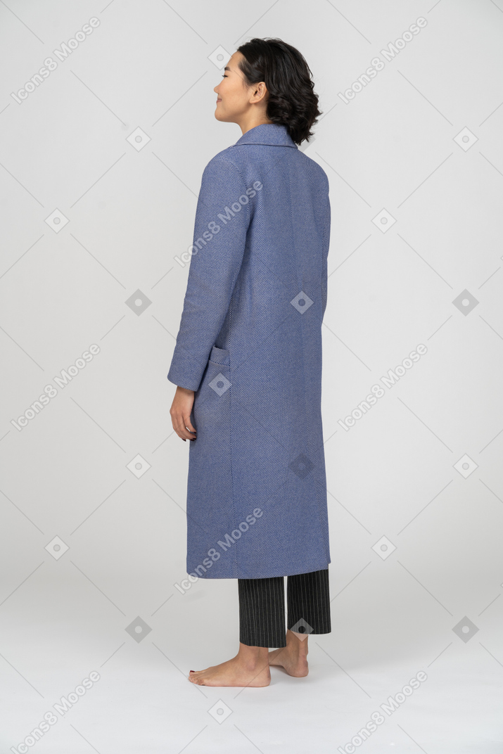 Вид сзади улыбающейся женщины в синем пальто