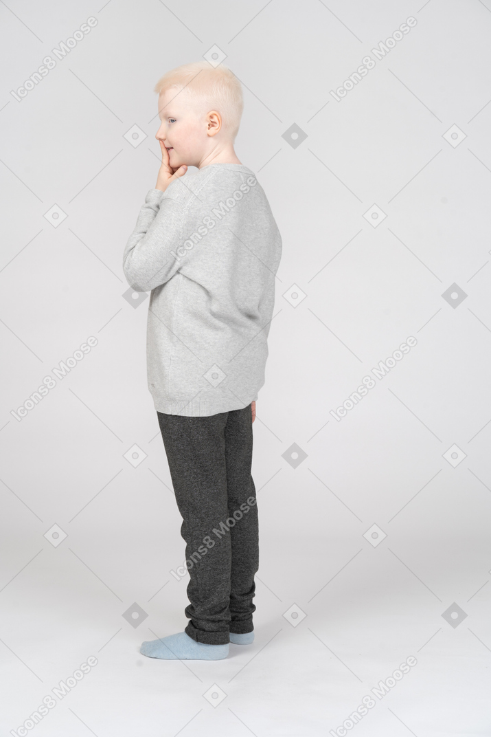 Side view of a sly boy putting finger up to lips
