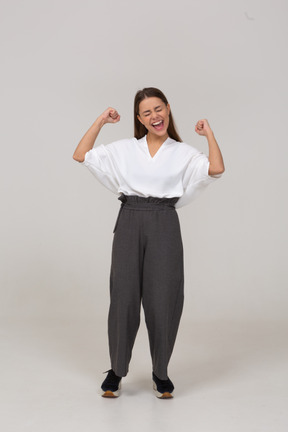 Front view of a happy young lady in office clothing raising hands