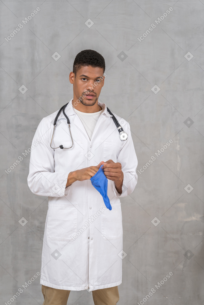 Männlicher arzt, der medizinische handschuhe anzieht