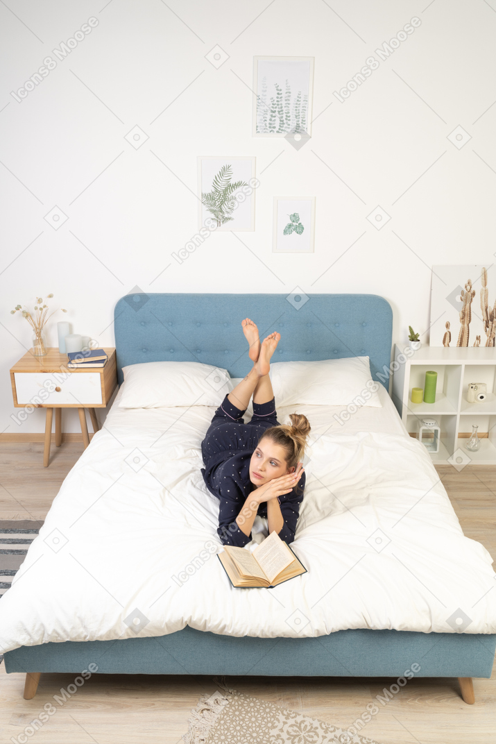 一个梦想中的年轻女性在床上看书的前视图