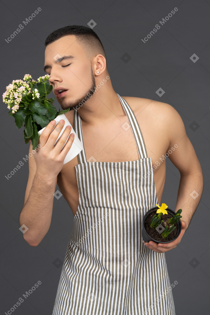 Naked young man sniffing flowers