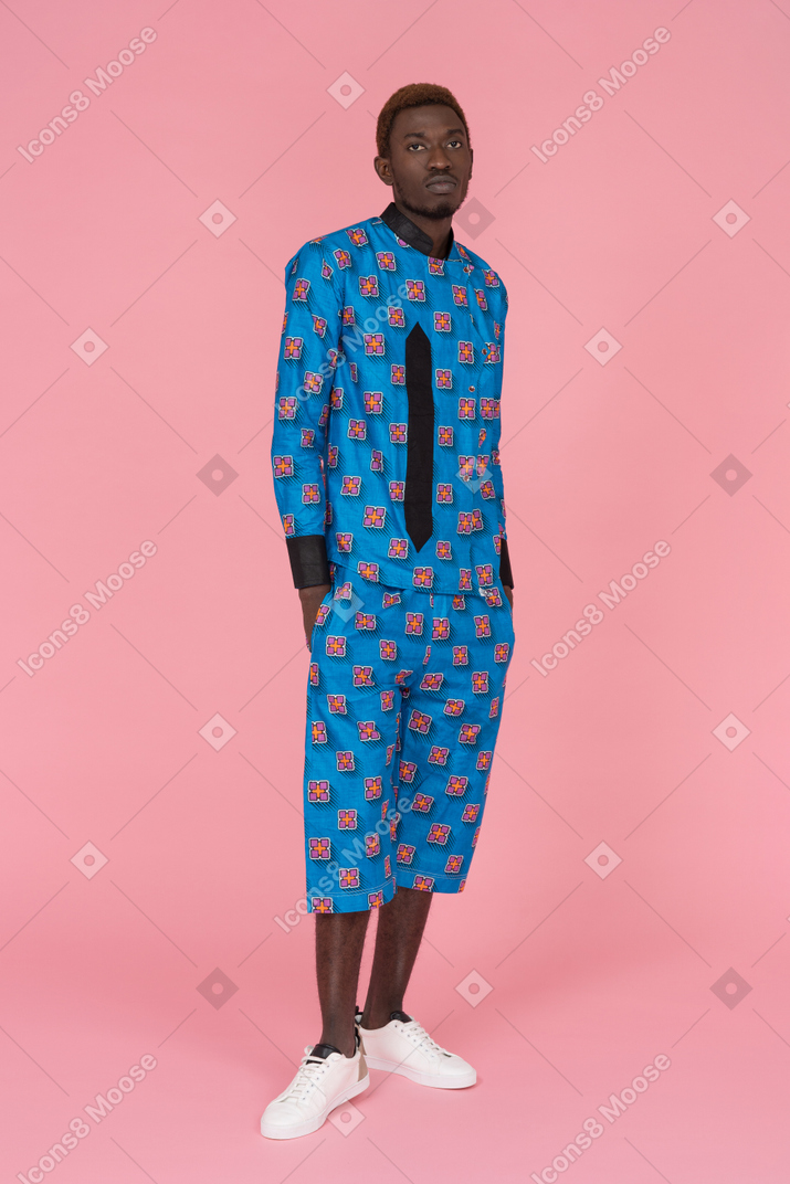 Homem negro de pijama azul em pé sobre fundo rosa