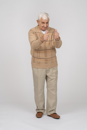 Vue de face d'un vieil homme heureux dans des vêtements décontractés montrant les pouces vers le haut