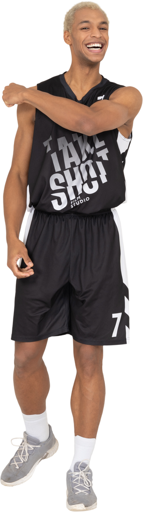 Vista frontal de un sonriente joven jugador de baloncesto tocando el hombro