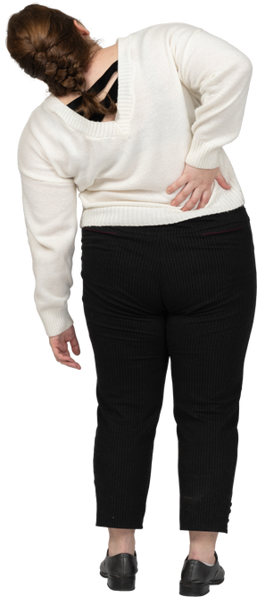 Женщина больших размеров в белом свитере страдает от боли в пояснице