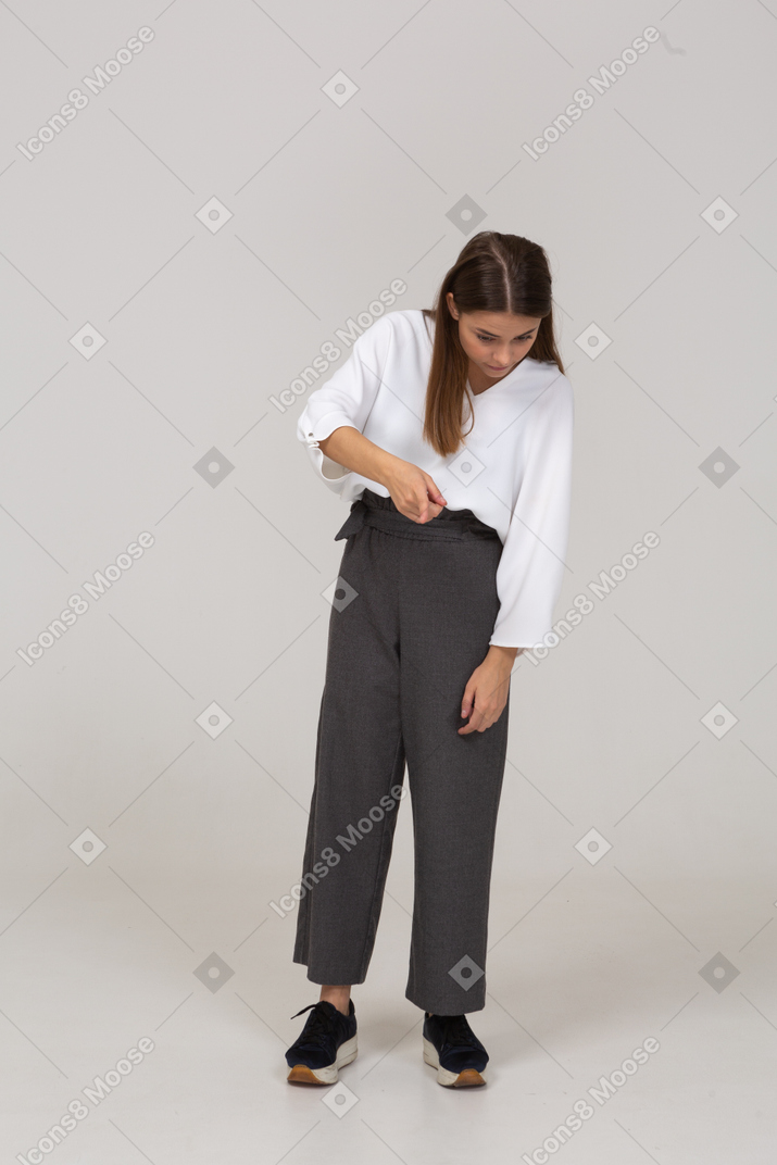 Вид спереди молодой леди в офисной одежде указывая пальцем