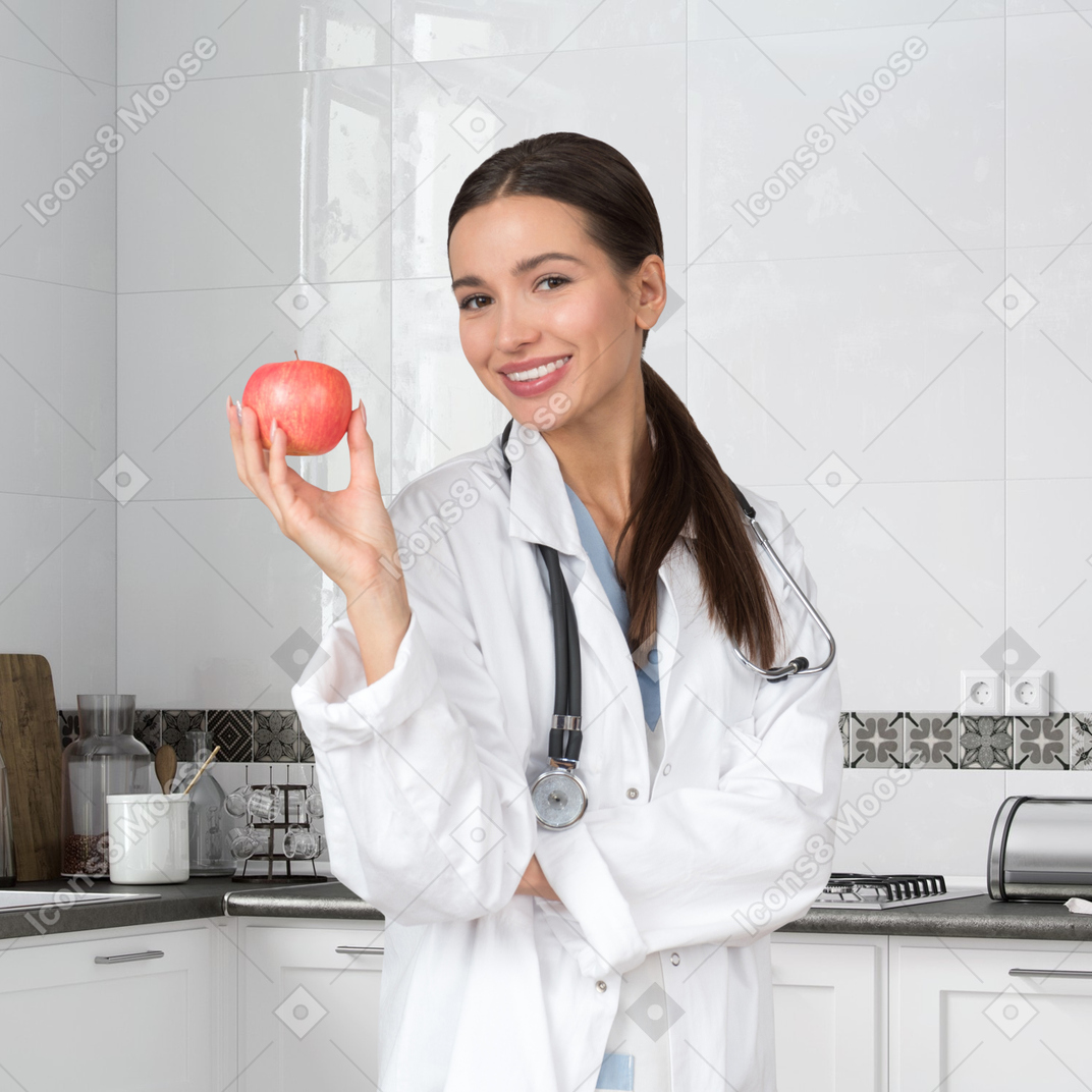A woman in a white lab coat holding an apple