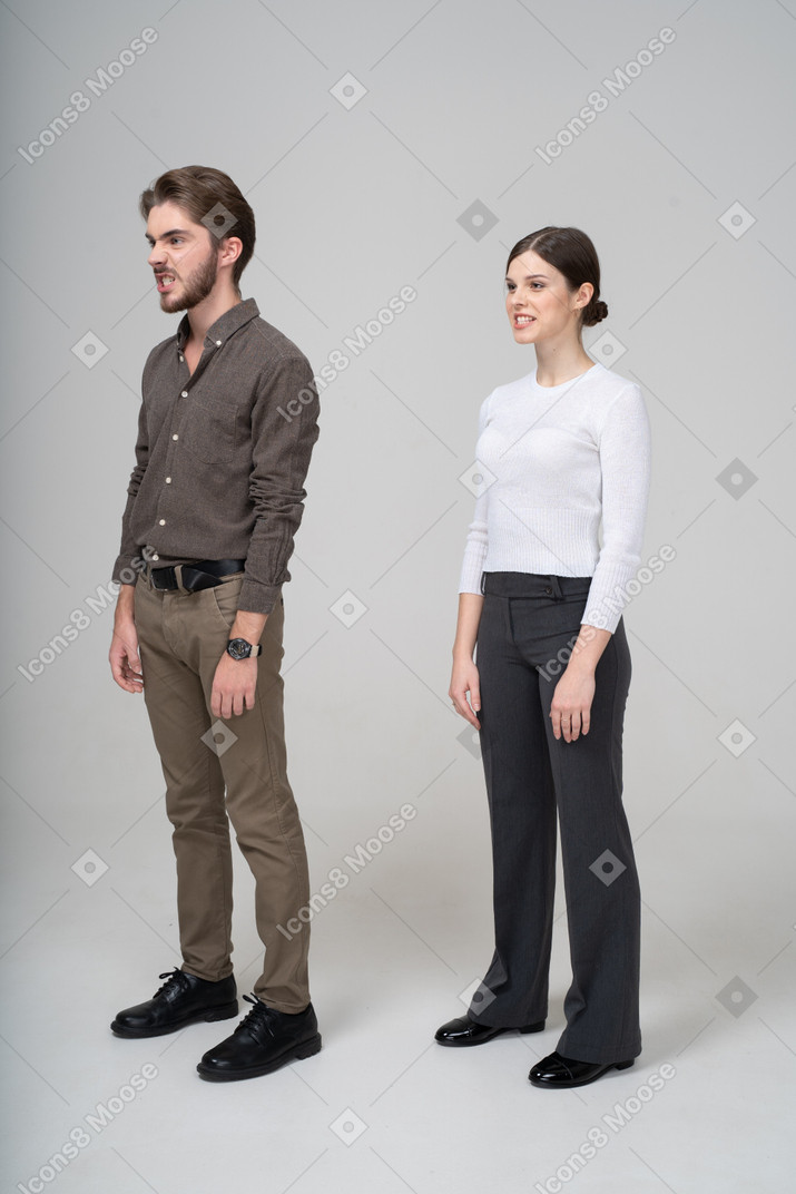 Трехчетвертный вид молодой пары в офисной одежде, стиснутой зубами