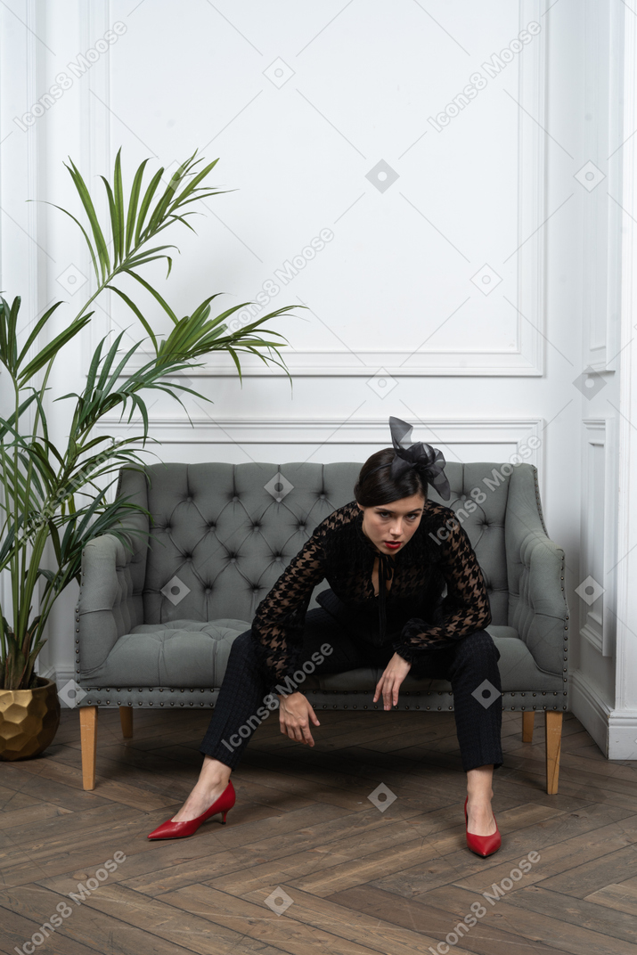 Woman sitting on couch with legs wide apart
