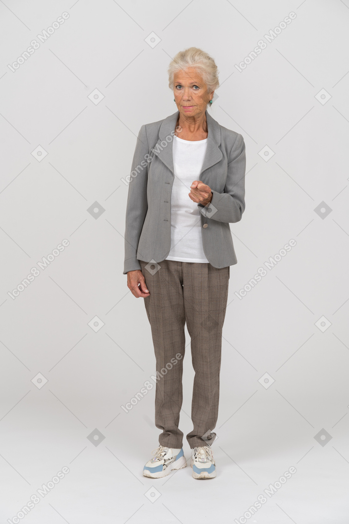 Front view of an old woman in suit pointing with a finger