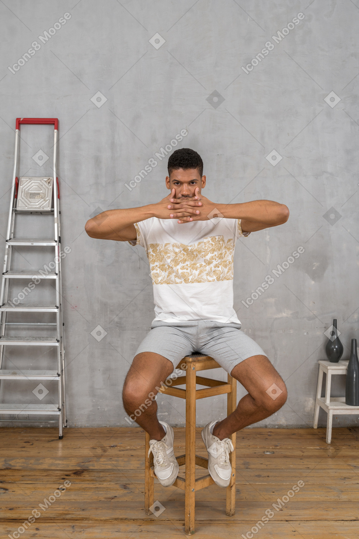 Мужчина сидит на стуле со скрещенными пальцами