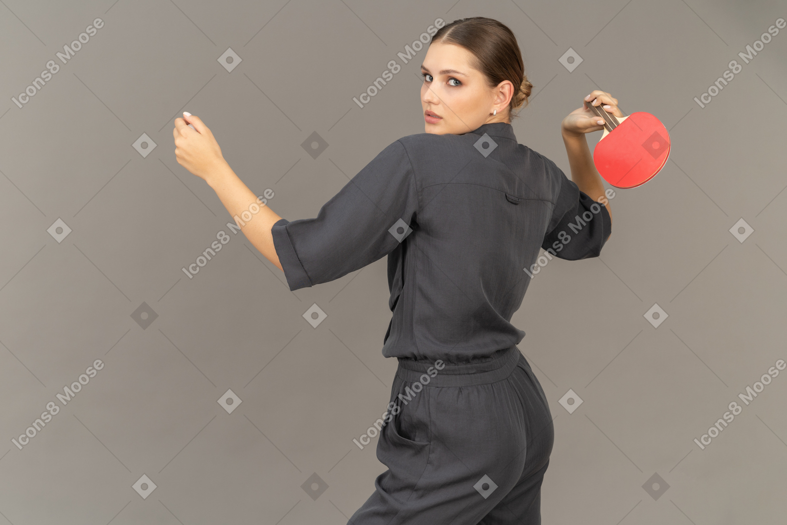 Three-quarter back view of young woman in a jumpsuit playing table tennis