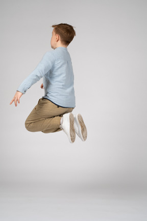 Side view of a boy in white sneakers jumping high in the air