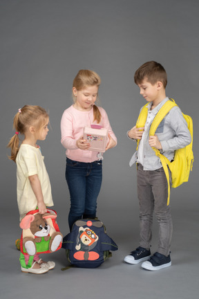 Drei kinder mit süßen rucksäcken und spielzeug