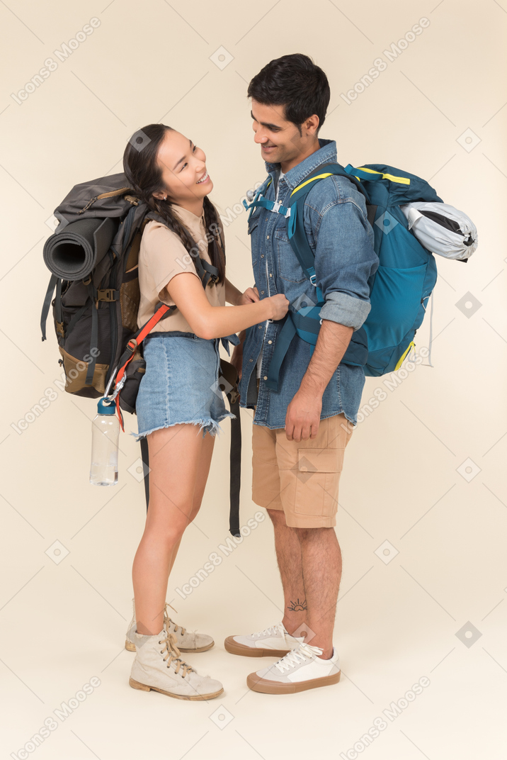 Laughing interracial couple with huge backpacks hugging