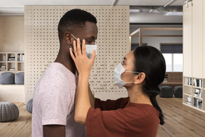 A woman in face mask touching man's face in face mask