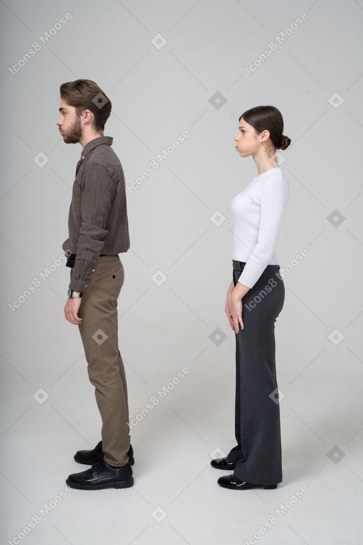 Side view of a young couple in office clothing blowing cheeks
