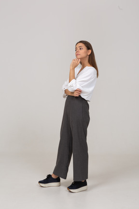Three-quarter view of a thoughtful young lady in office clothing touching chin