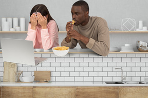 A man and a woman watching a movie at a kitchen counter