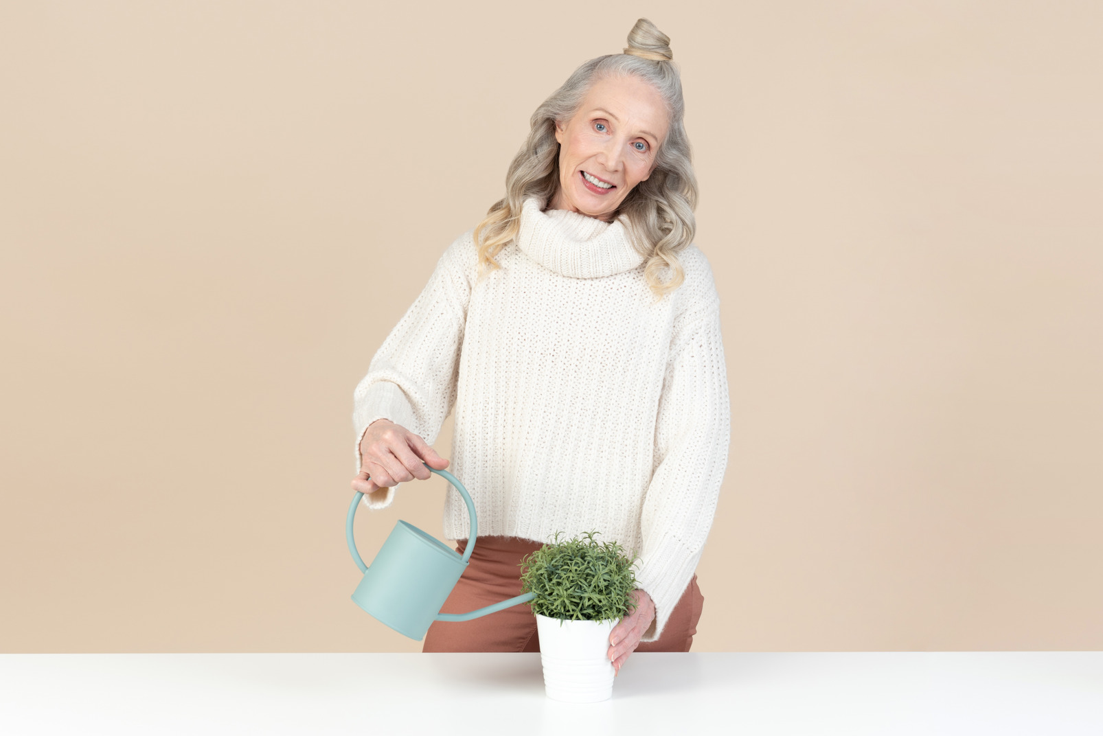 Smiling old woman watering plants