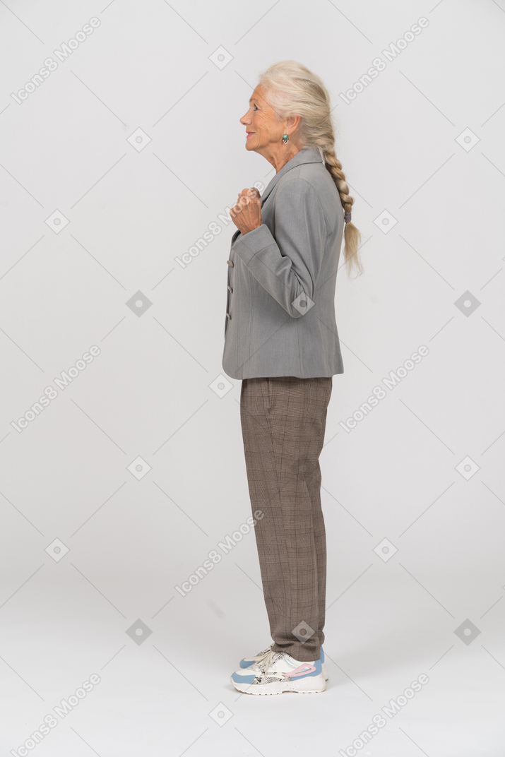 Side view of a happy old lady in suit showing fist