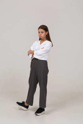 Vista de tres cuartos de una joven en ropa de oficina soplando mejillas y cruzando los brazos