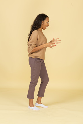 Vista lateral de una mujer joven sorprendida de piel oscura extendiendo sus dedos