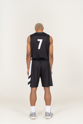 Back view of a young male basketball player standing still & looking down