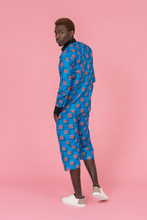 Black man in blue pajamas standing on the pink background