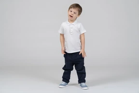 Confused little boy standing with arms at sides
